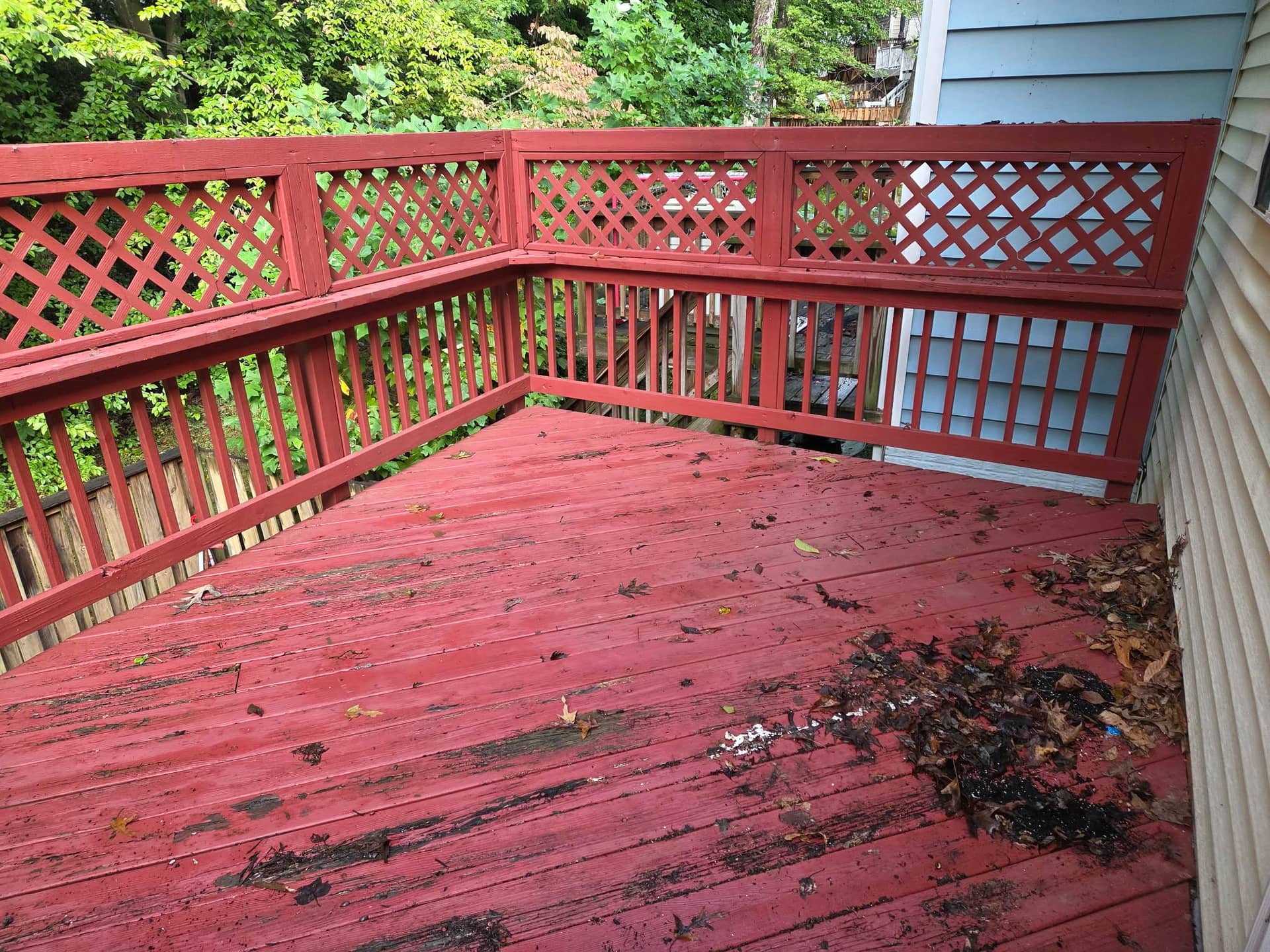 Worn red deck boards with peeling finish and lattice panels above the railing.