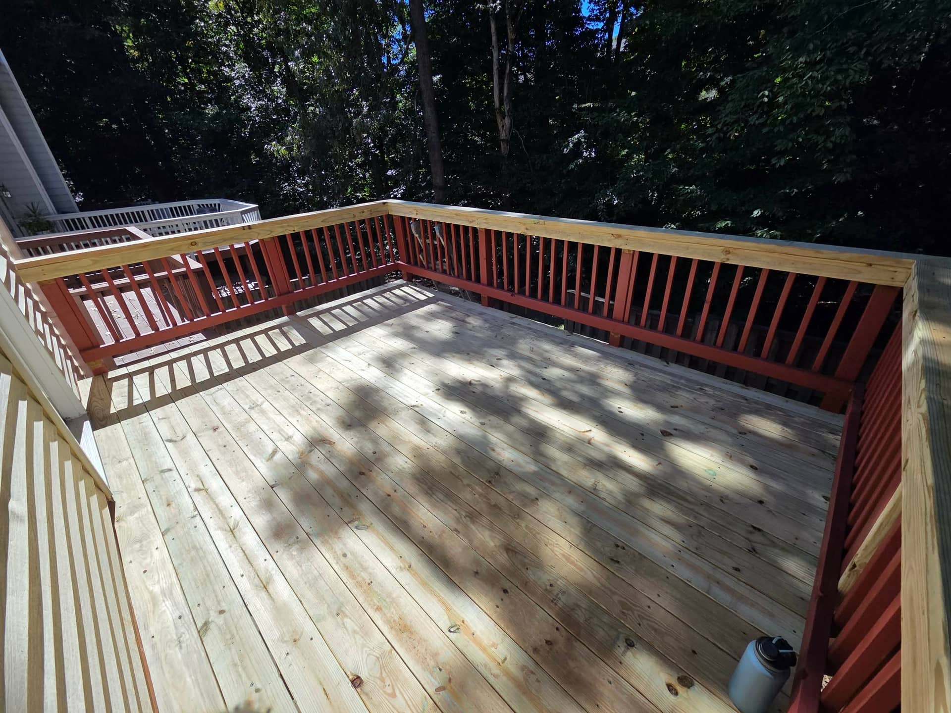 Replacement wood deck boards and new top rails with retained red balusters.