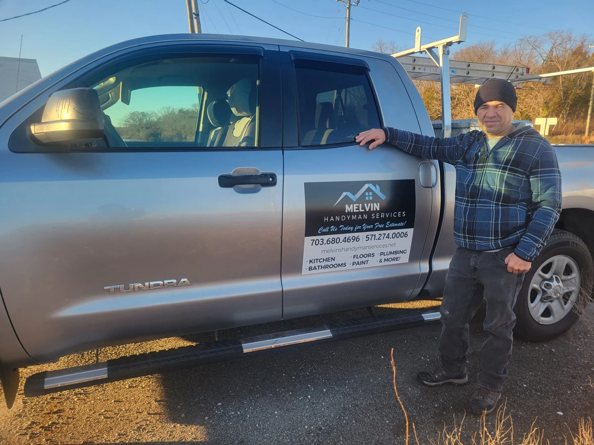 Melvin standing beside his silver work truck with Melvin's Handyman Services signage