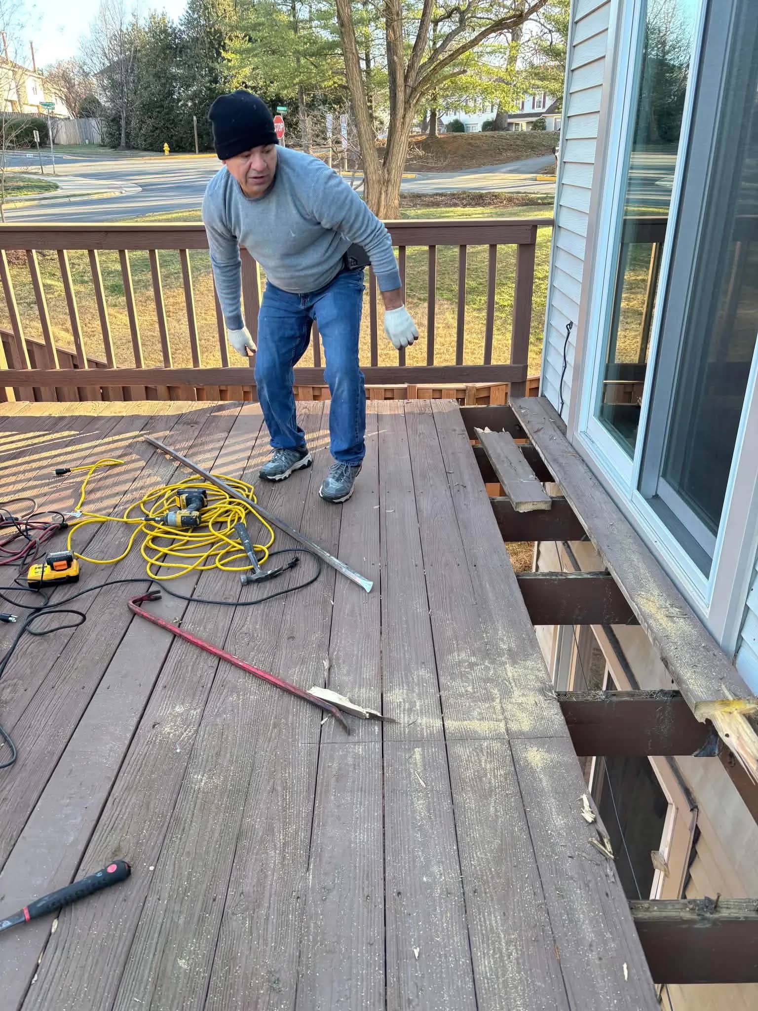 Melvin inspecting and repairing wood framing on an outdoor deck